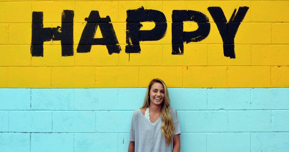 girl in front of wall that says happy